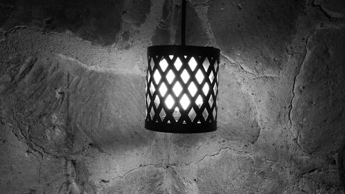 Close-up of electric lamp hanging from metal grate