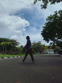 Side view of man standing on road against sky