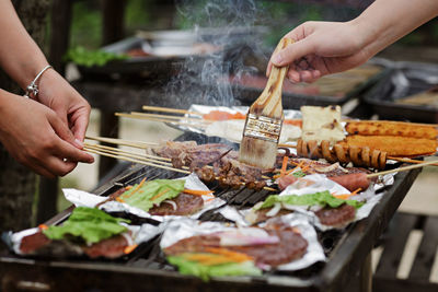 Cropped hand preparing food on barbecue grill