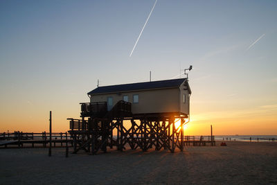 Lifeguard hut on beach against sky during sunset