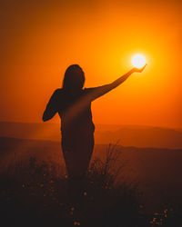 Rear view of silhouette woman standing on street during sunset