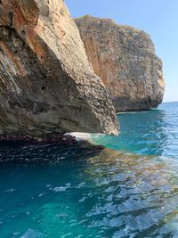 Rock formation in sea against sky