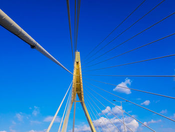 Low angle view of suspension bridge against blue sky