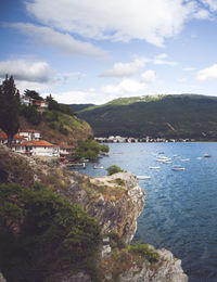 Scenic view of sea by townscape against sky