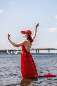 Rear view of woman standing in sea against sky