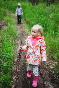 Little girl walking in the forest and little boy behind her