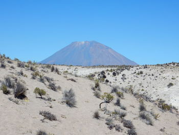 Scenic view of desert land against clear blue sky