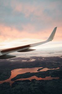 Close-up of airplane wing against sky during sunset