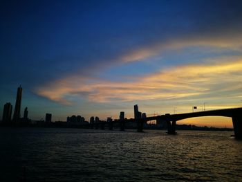 Silhouette of bridge over river during sunset