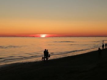 Silhouette man riding horse on beach against sky during sunset