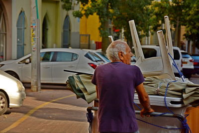 Rear view of woman sitting on street in city