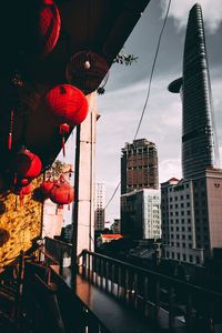 Low angle view of lanterns hanging by buildings against sky