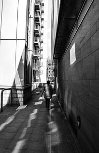 Rear view of man walking on modern buildings in city