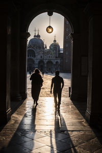 Rear view of man and woman walking in archway