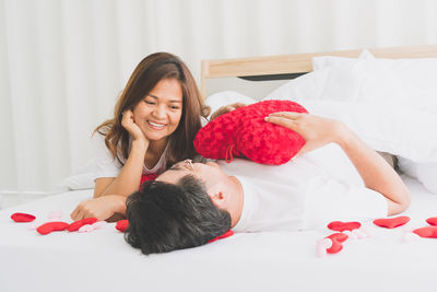 Portrait of happy woman lying down on bed