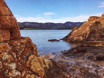 Rock formations by sea against sky