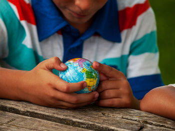 Midsection of boy looking at globe on table