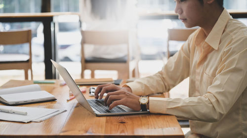 Freelance young man using a laptop computer to create customer project, he sits online working.