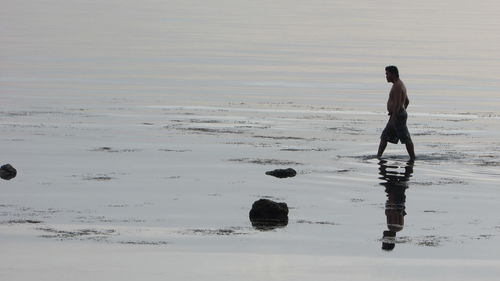 Full length of boy standing on wet sand at beach