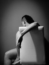 Side view of woman sitting against wall