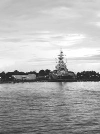 View of buildings by river against cloudy sky