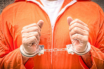 Close-up of human hands against orange wall