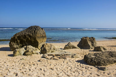 Rocks on beach against clear sky