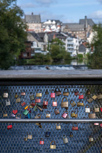 Close-up of metal railing by river against buildings in city