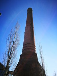 Low angle view of smoke stack against clear blue sky