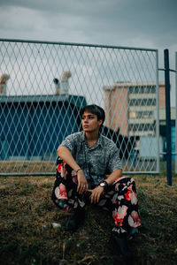 Full length of boy sitting by fence