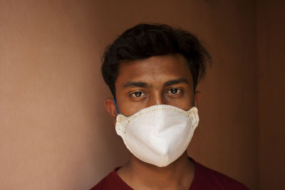 Portrait of young man with mask against wall