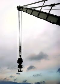 Low angle view of silhouette of crane seaport against sky
