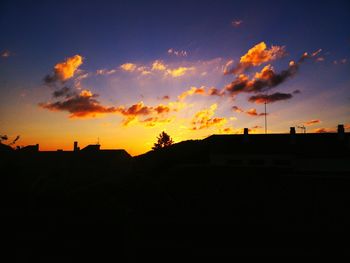 Silhouette houses against sky during sunset