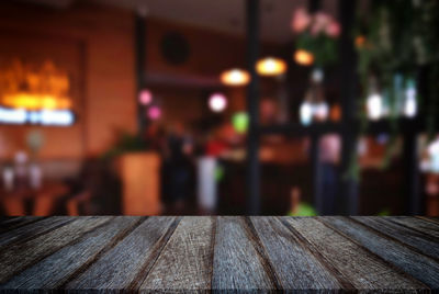 Close-up of wooden table against illuminated building
