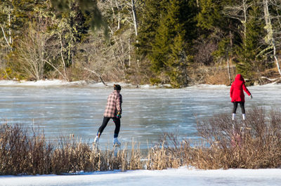 Two skaters with backs to camera on frozen lake