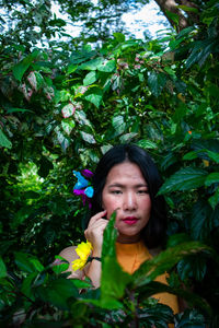 Portrait of young woman standing amidst plants