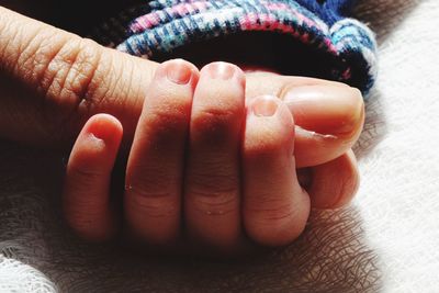 Cropped image of baby and parent holding hands