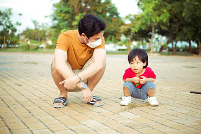 Side view of boy sitting on footpath