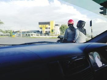 Rear view of man and woman in car against sky