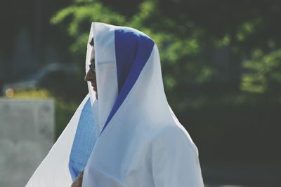 Close-up of woman with umbrella standing against blurred background