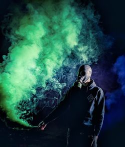 Man wearing gas mask while holding green distress flare at night