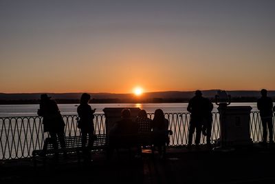 Silhouette people standing on beach against clear sky during sunset