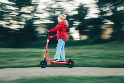 Full length of girl riding push scooter at park