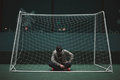 Full length of man sitting on soccer field