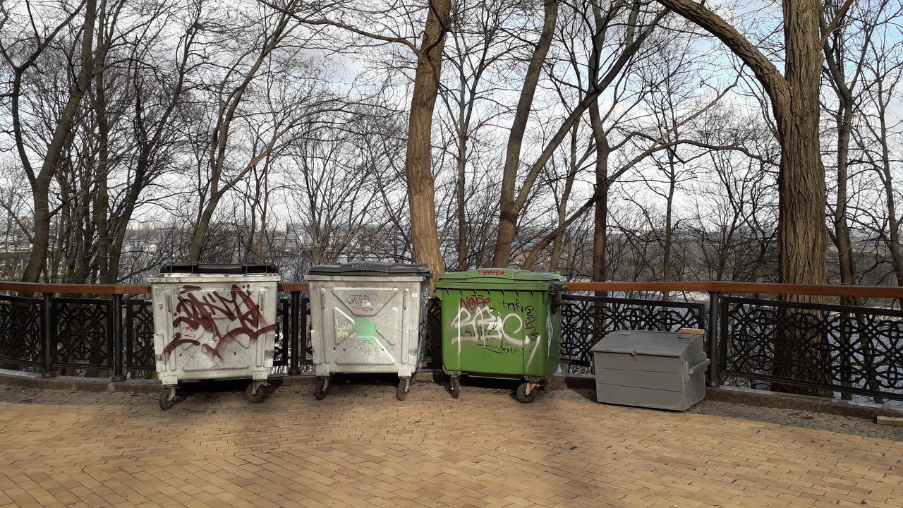 GARBAGE BIN AGAINST BARE TREES AND PLANTS