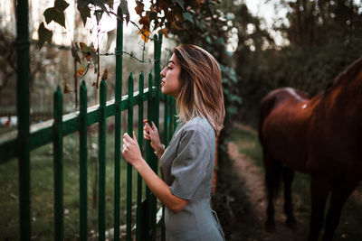 Side view of teenage girl standing by tree