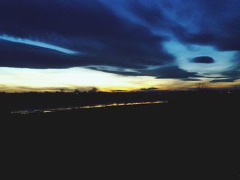 Scenic view of landscape against cloudy sky at dusk