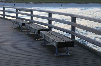 Empty bench on pier during winter