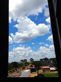 Buildings and trees against sky seen through window