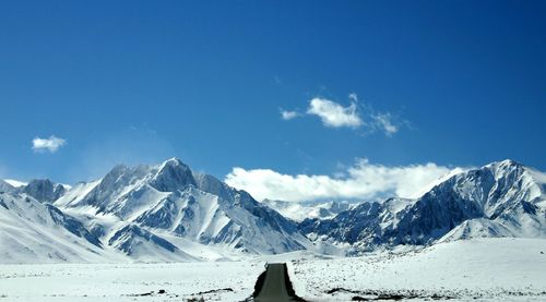 Empty road leading towards snowcapped mountain against sky